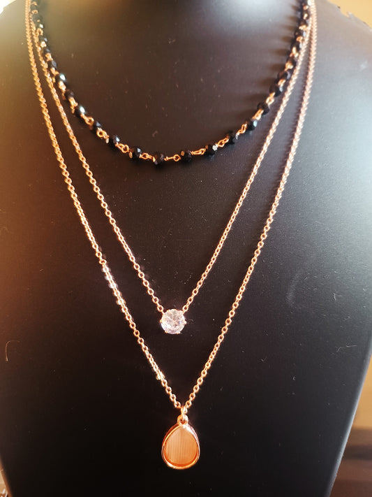 A rose-gold-plated three-layered oval-diamond neckpiece displayed on a mannequin.