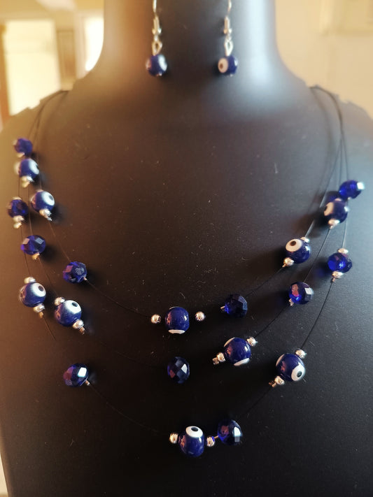 A three-layered necklace with blue beads and metallic accents displayed on a mannequin bust.