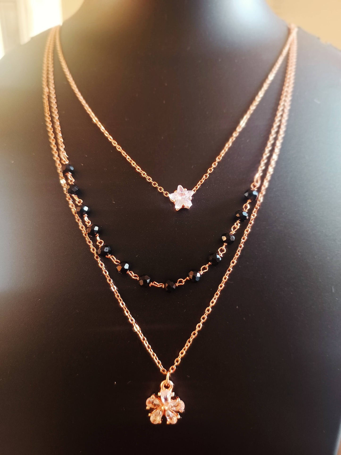 A three-layered rose-gold plated diamond star neckpiece displayed on a mannequin bust.