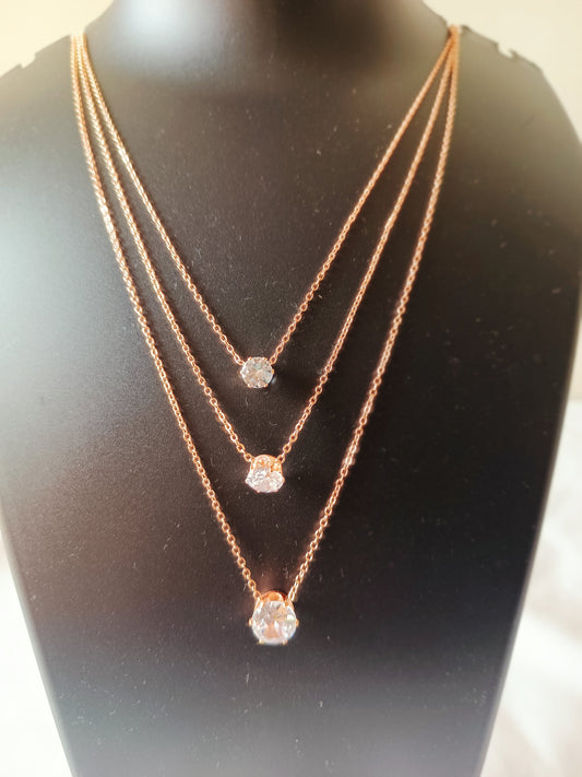 A three-layered rose gold-plated diamond neckpiece displayed on a mannequin bust.