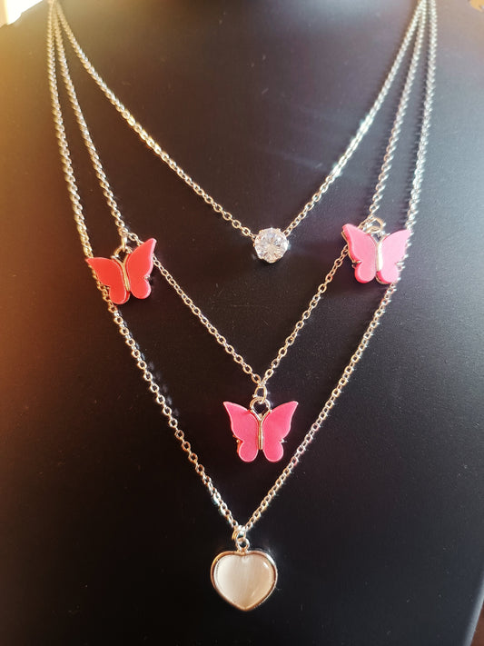 A silver-plated three-layered heart-shaped pink butterflies neckpiece displayed on a mannequin.