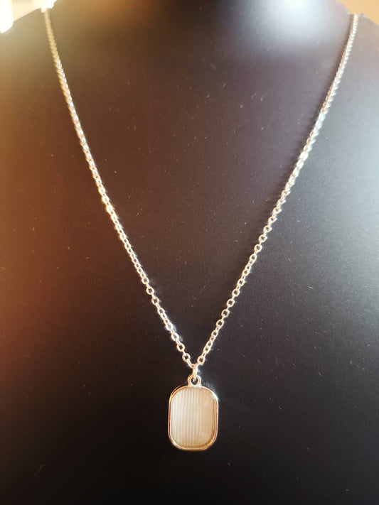 A silver-plated square-shaped neckpiece displayed on a mannequin bust.