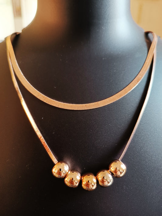 A gold-plated double-layered beads neckpiece displayed on a mannequin bust.