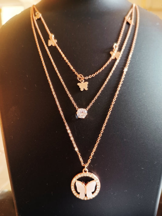 A rose-gold plated three-layered peach colored butterfly-shaped neckpiece displayed on a mannequin.