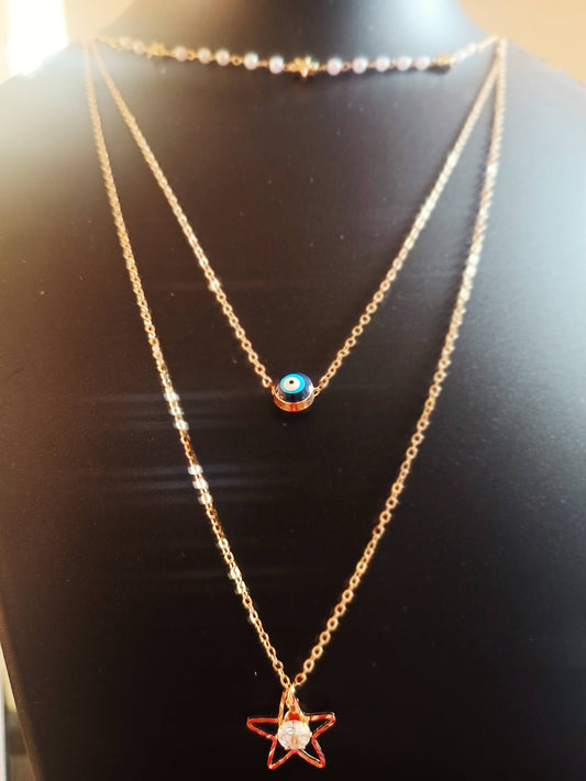 A three layered gold-plated necklace with diamond studs, featuring a blue evil eye-star pearl motif, displayed on a mannequin.