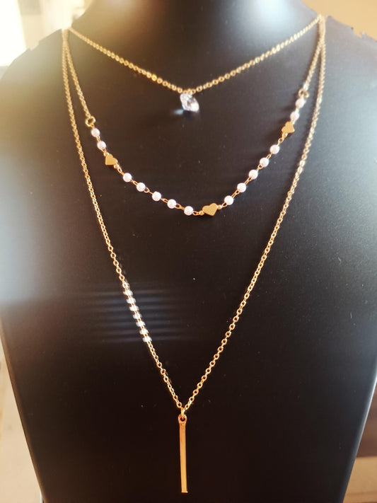A gold-plated solitaire pearl neckpiece with multiple layers and a single central pearl on a mannequin bust.