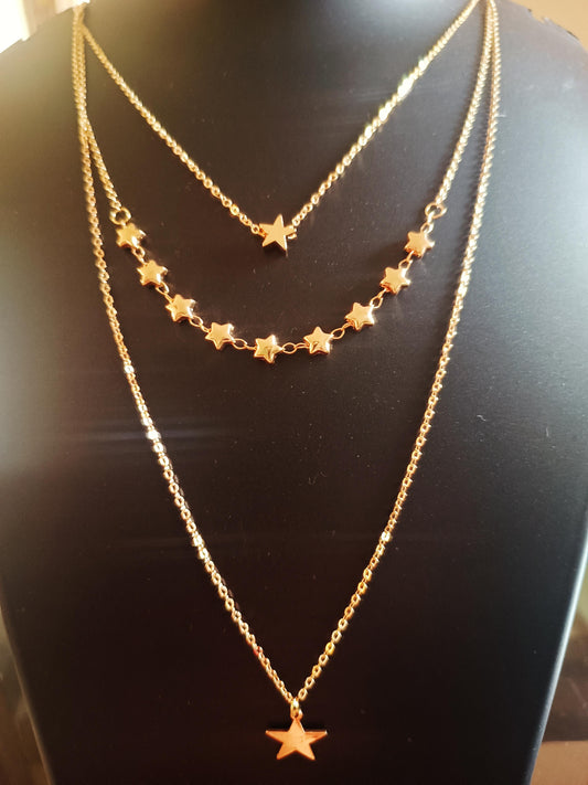 A three layered gold-plated necklace with star-shaped pendants displayed on a mannequin.