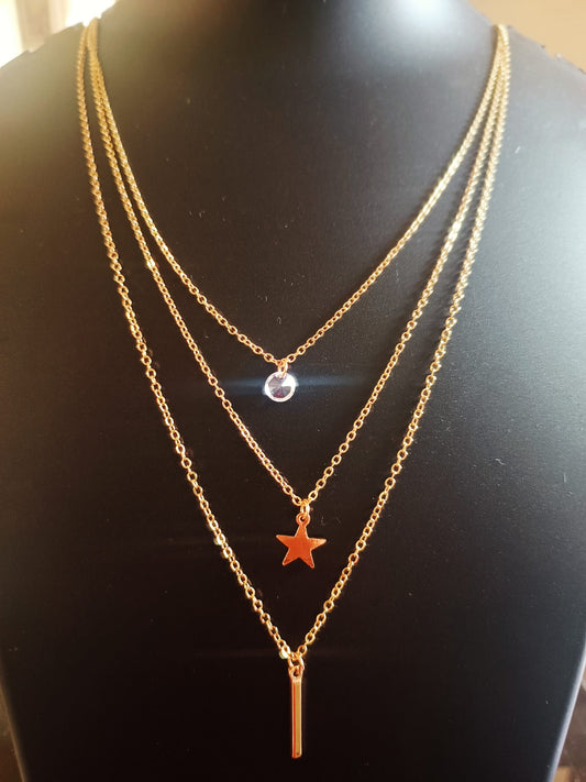 A three layered gold-plated neckpiece with a star-solitaire design displayed on a mannequin.