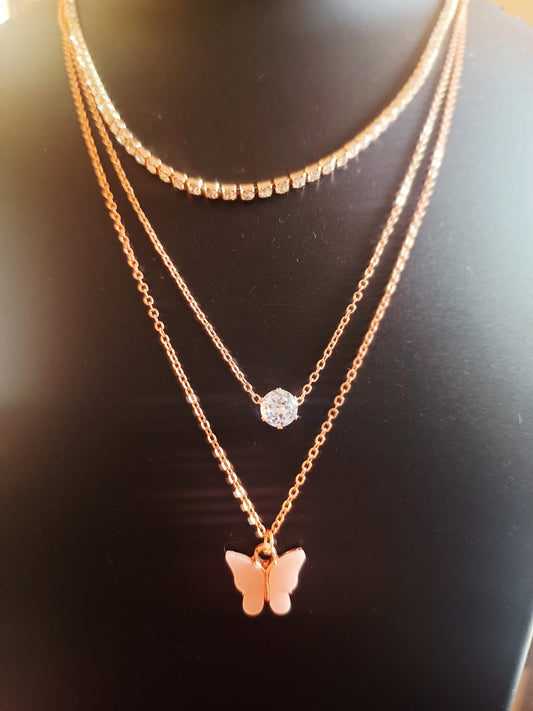 A rose-gold-plated three-layered diamond-studded butterfly neckpiece with a cream-colored charm on the bottom layer, displayed on a mannequin.