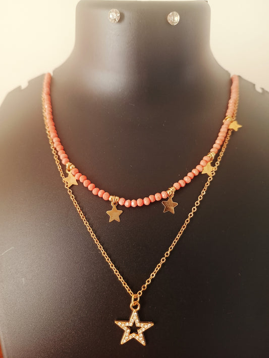A gold-plated orange beads double-layered star neckpiece with earrings displayed on a mannequin bust.