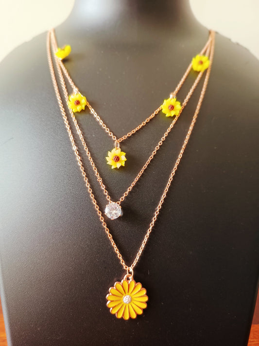 A rose-gold plated three-layered yellow daisy flowers neckpiece displayed on a mannequin bust.