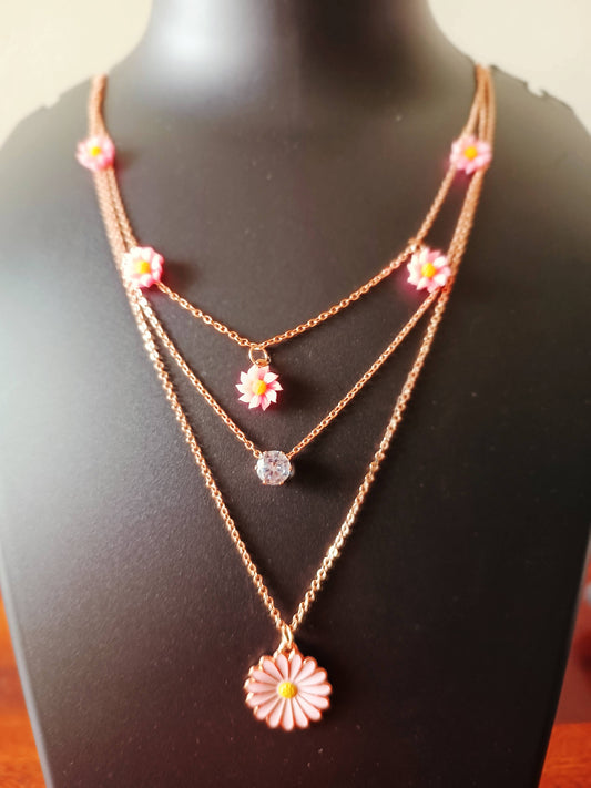 A rose-gold plated three-layered pink daisy flowers neckpiece displayed on a mannequin.